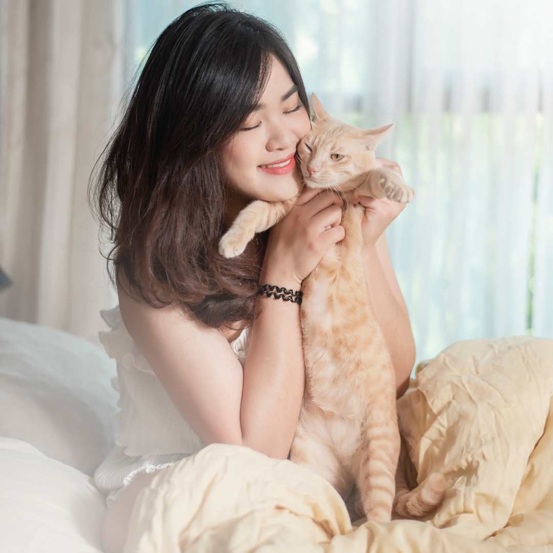 A person is sitting on a bed holding a cat